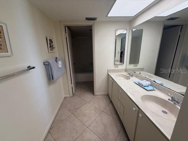 14950 Gulf Blvd Unit 603, Madeira Beach, FL 33708 - bathroom featuring tile patterned floors, double vanity, and baseboards