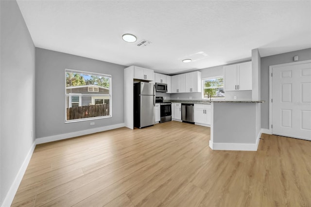 8504 N 17th St, Tampa, FL 33604 - kitchen with appliances with stainless steel finishes, baseboards, white cabinets, and light wood finished floors