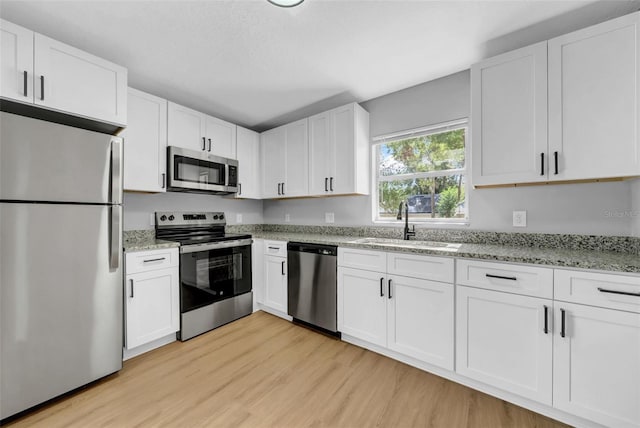 8504 N 17th St, Tampa, FL 33604 - kitchen with stainless steel appliances, light wood-style floors, a sink, and white cabinetry