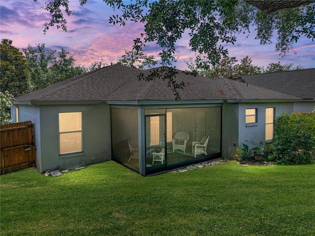 18003 Arbor Crest Dr, Tampa, FL 33647 - back of house at dusk with roof with shingles, a sunroom, and stucco siding