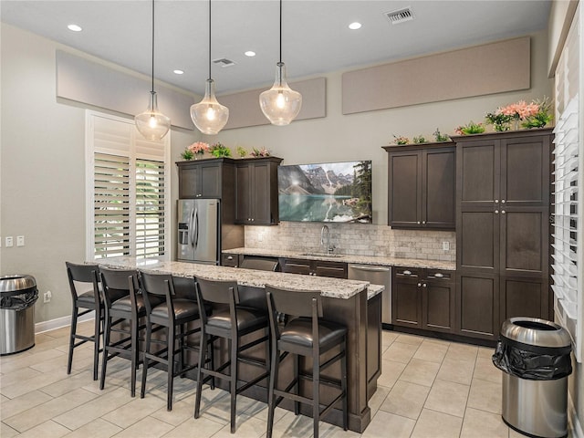 18003 Arbor Crest Dr, Tampa, FL 33647 - kitchen featuring stainless steel appliances, tasteful backsplash, a kitchen island, dark brown cabinets, and a breakfast bar
