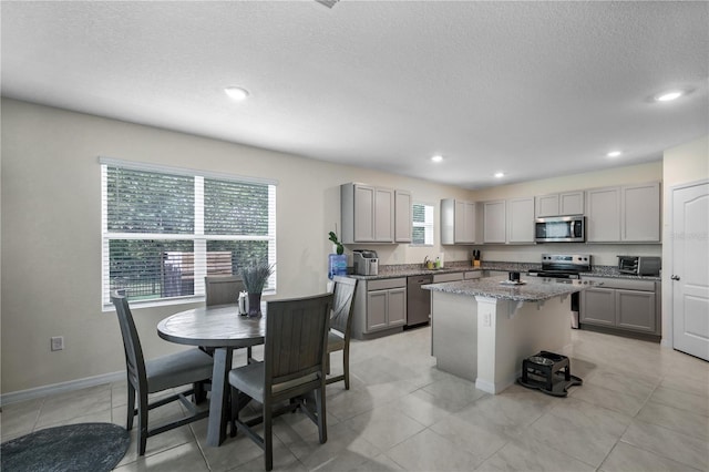 5189 Greenheart Ave, Mount Dora, FL 32757 - kitchen featuring gray cabinets, stainless steel appliances, a center island, recessed lighting, and light stone countertops