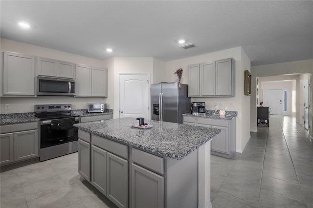 5189 Greenheart Ave, Mount Dora, FL 32757 - kitchen with stainless steel appliances, gray cabinets, a center island, light stone counters, and recessed lighting