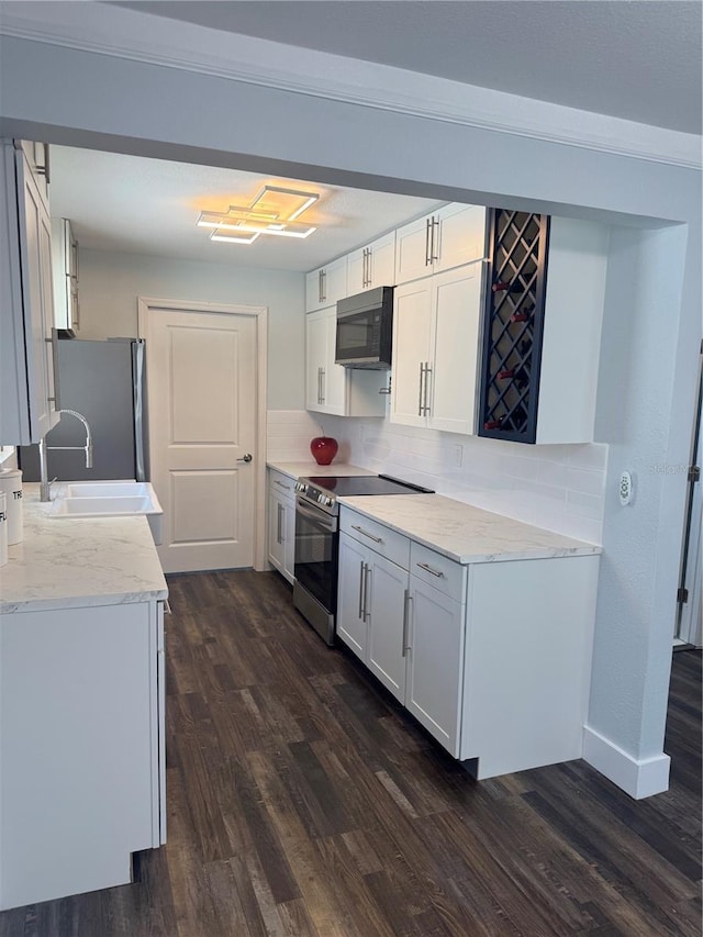 3008 E 38th Ave, Tampa, FL 33610 - kitchen with stainless steel appliances, a sink, dark wood-type flooring, backsplash, and white cabinetry
