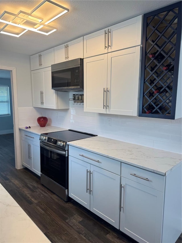 3008 E 38th Ave, Tampa, FL 33610 - kitchen featuring stainless steel range with electric stovetop, backsplash, dark wood finished floors, light stone countertops, and white cabinets