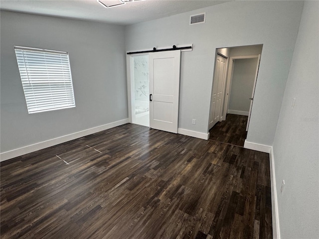 3008 E 38th Ave, Tampa, FL 33610 - unfurnished bedroom with a barn door, dark wood finished floors, and baseboards