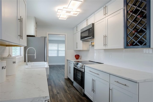 3008 E 38th Ave, Tampa, FL 33610 - kitchen featuring stainless steel appliances, backsplash, dark wood finished floors, and white cabinets