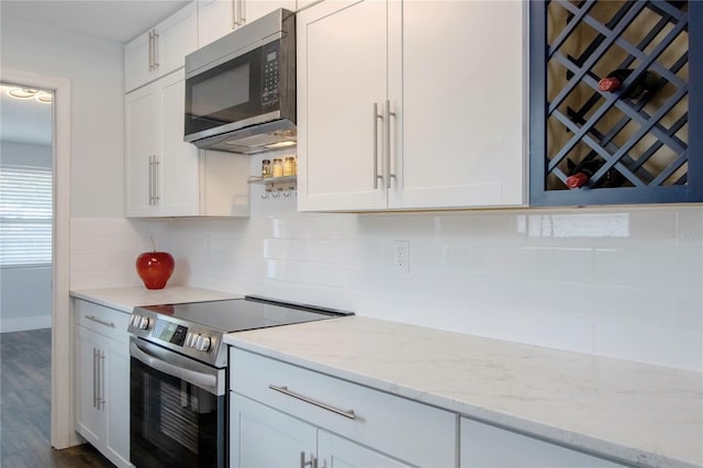 3008 E 38th Ave, Tampa, FL 33610 - kitchen featuring stainless steel appliances, white cabinets, tasteful backsplash, light stone counters, and dark wood finished floors