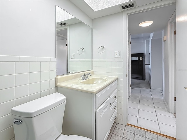 1 Boca Ciega Point Blvd Unit 215, Saint Petersburg, FL 33708 - half bath featuring tile walls, toilet, vanity, and a wainscoted wall