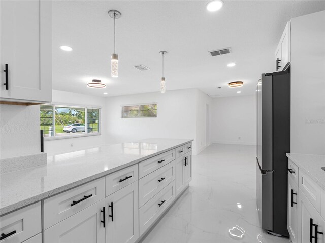 302 Patty Dr, Oldsmar, FL 34677 - kitchen with freestanding refrigerator, recessed lighting, white cabinets, light marble finish flooring, and light stone counters
