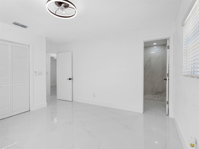 302 Patty Dr, Oldsmar, FL 34677 - unfurnished bedroom featuring marble look tiles, a closet, and ensuite bath