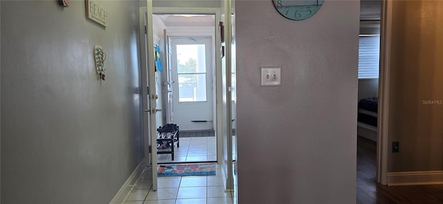 hallway with baseboards, tile patterned floors, and a textured wall