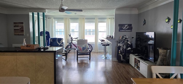 living room with ceiling fan, ornamental molding, wood finished floors, baseboards, and a textured ceiling