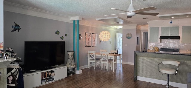 living room featuring a ceiling fan, crown molding, a textured ceiling, wood finished floors, and baseboards