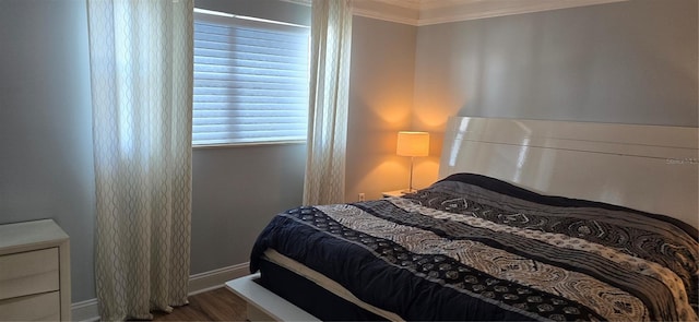 bedroom featuring ornamental molding, baseboards, and wood finished floors