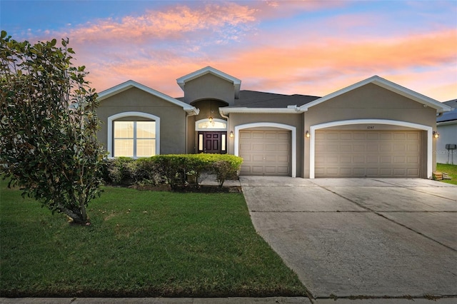view of front of house with a garage, stucco siding, concrete driveway, and a lawn