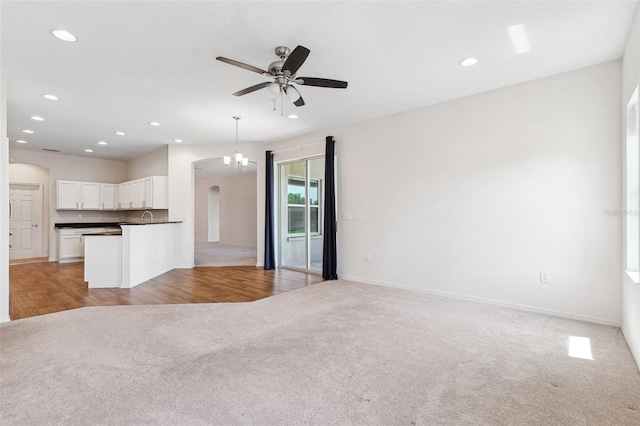 unfurnished living room featuring light carpet, ceiling fan, arched walkways, recessed lighting, and baseboards