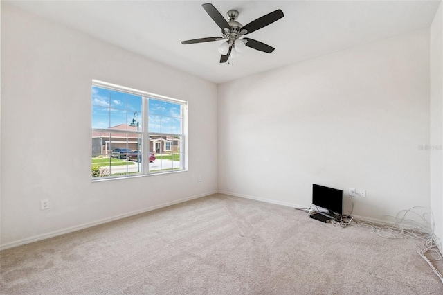 spare room with light carpet, ceiling fan, and baseboards