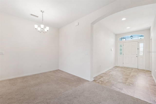 entryway with arched walkways, a chandelier, baseboards, and light colored carpet