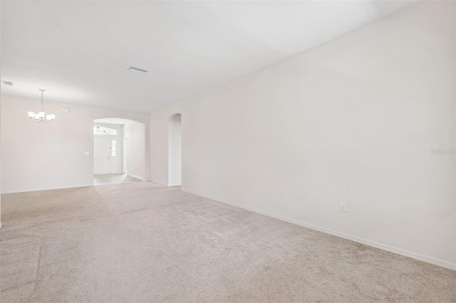 unfurnished room featuring a chandelier, arched walkways, light carpet, and baseboards