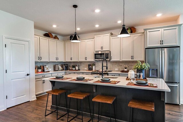 17020 Cercis Loop, Clermont, FL 34711 - kitchen with appliances with stainless steel finishes, light countertops, a kitchen bar, dark wood finished floors, and recessed lighting