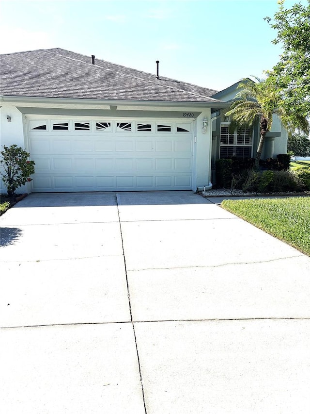 19420 Haskell Pl, Land O Lakes, FL 34638 - view of front of home with a garage, concrete driveway, stucco siding, and a shingled roof