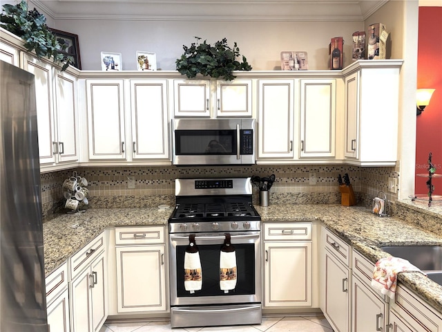 19420 Haskell Pl, Land O Lakes, FL 34638 - kitchen with appliances with stainless steel finishes, ornamental molding, backsplash, cream cabinetry, and light tile patterned floors