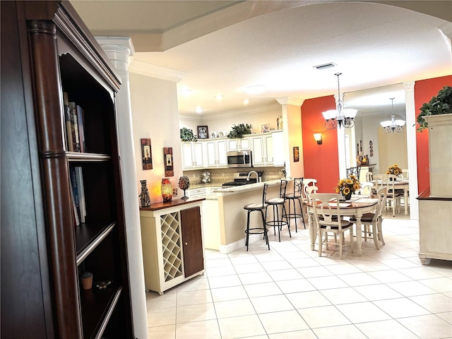 19420 Haskell Pl, Land O Lakes, FL 34638 - kitchen featuring stainless steel appliances, light tile patterned flooring, a kitchen breakfast bar, backsplash, and ornamental molding