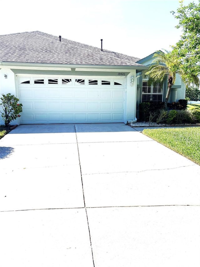 19420 Haskell Pl, Land O Lakes, FL 34638 - view of front of home featuring concrete driveway, a garage, and stucco siding