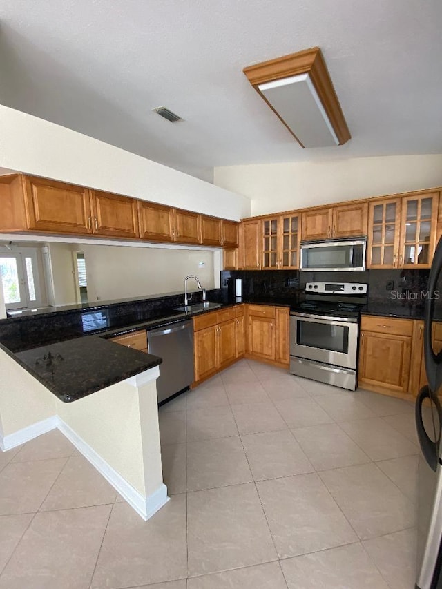 11014 Peking Pl, Tampa, FL 33624 - kitchen featuring appliances with stainless steel finishes, brown cabinetry, decorative backsplash, a sink, and light tile patterned floors