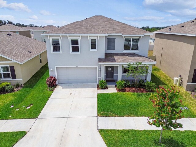33524 Elm Hill Br, Wesley Chapel, FL 33545 - traditional-style house with stucco siding, a garage, roof with shingles, driveway, and a front yard