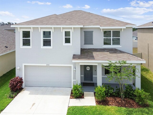 33524 Elm Hill Br, Wesley Chapel, FL 33545 - view of front of home featuring a shingled roof, stucco siding, covered porch, and an attached garage