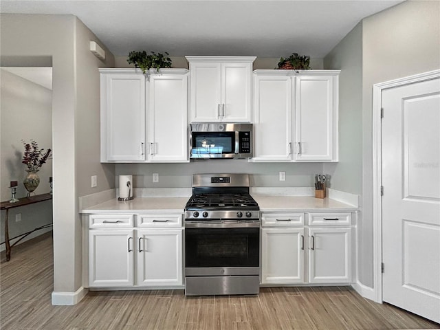 16913 Anchor Root St, Wimauma, FL 33598 - kitchen with appliances with stainless steel finishes, light wood finished floors, white cabinetry, and light countertops