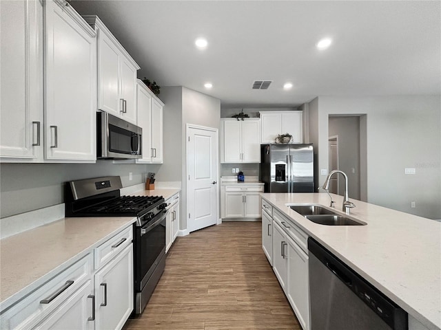 16913 Anchor Root St, Wimauma, FL 33598 - kitchen with stainless steel appliances, a sink, recessed lighting, white cabinetry, and wood finished floors