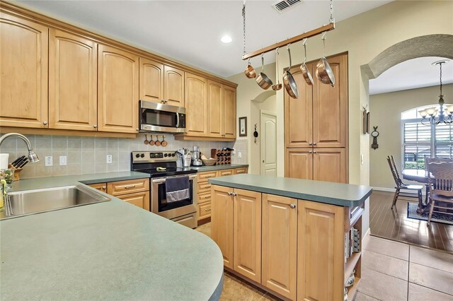 12012 Cromwell Way, Spring Hill, FL 34609 - kitchen featuring appliances with stainless steel finishes, a sink, arched walkways, a chandelier, and a kitchen island