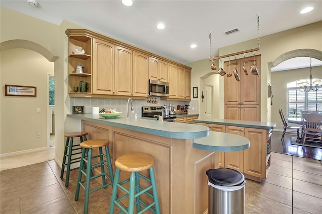 12012 Cromwell Way, Spring Hill, FL 34609 - kitchen featuring appliances with stainless steel finishes, arched walkways, backsplash, a peninsula, and open shelves