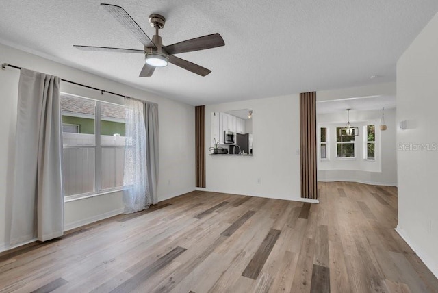 5865 Meadowpark Pl, Lithia, FL 33547 - unfurnished living room featuring a textured ceiling, light wood-style flooring, a ceiling fan, baseboards, and a chandelier