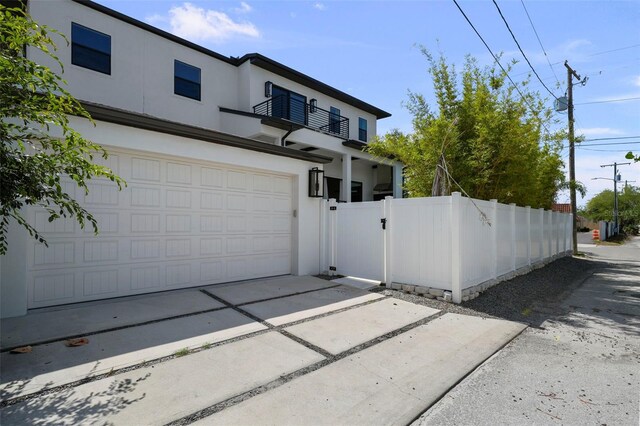 403 E Davis Blvd, Tampa, FL 33606 - view of front of property with a balcony, stucco siding, a gate, concrete driveway, and a garage