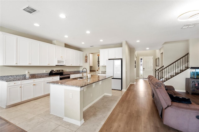 4917 Eagle Rock Dr, Wimauma, FL 33598 - kitchen featuring white appliances, a sink, an island with sink, open floor plan, and dark stone counters