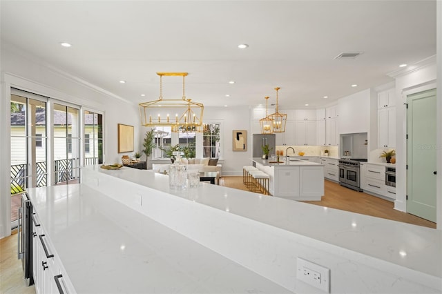 2200 N Glenwood Dr, Tampa, FL 33602 - kitchen with stainless steel appliances, a chandelier, white cabinets, ornamental molding, and backsplash
