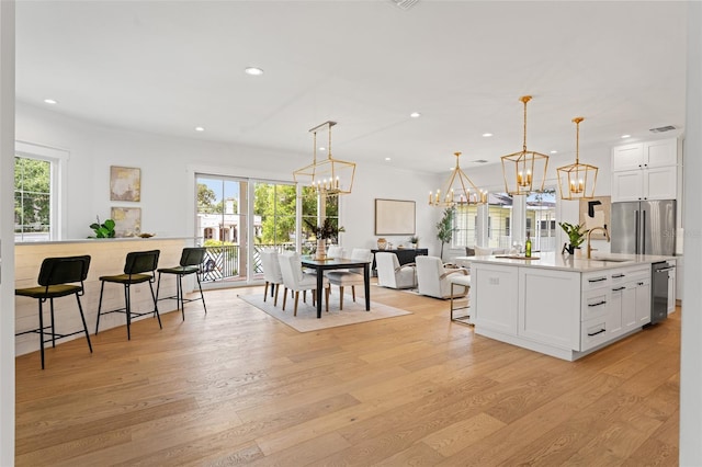 2200 N Glenwood Dr, Tampa, FL 33602 - kitchen featuring a kitchen bar, appliances with stainless steel finishes, a chandelier, light wood-type flooring, and white cabinets