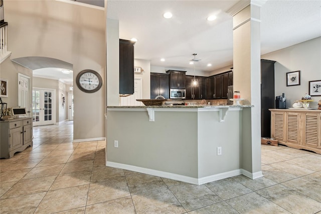 3530 Brook Crossing Dr, Brandon, FL 33511 - kitchen with appliances with stainless steel finishes, a breakfast bar area, stone countertops, arched walkways, and dark brown cabinets