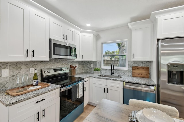 5624 62nd St N, Saint Petersburg, FL 33709 - kitchen featuring appliances with stainless steel finishes, a sink, white cabinetry, decorative backsplash, and light stone counters