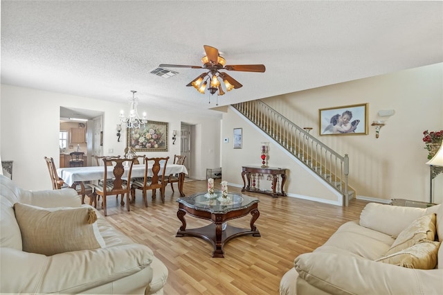 10311 Frog Pond Dr, Riverview, FL 33569 - living area with stairway, a ceiling fan, light wood finished floors, a chandelier, and a textured ceiling
