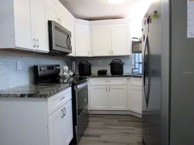 8996 Southern Comfort Dr, Largo, FL 33773 - kitchen with stainless steel appliances, wood finished floors, white cabinets, tasteful backsplash, and a textured ceiling