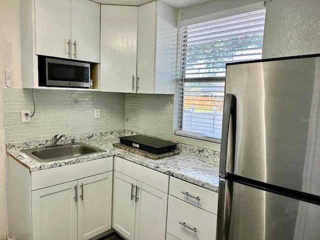 8996 Southern Comfort Dr, Largo, FL 33773 - kitchen with appliances with stainless steel finishes, a sink, backsplash, and white cabinetry