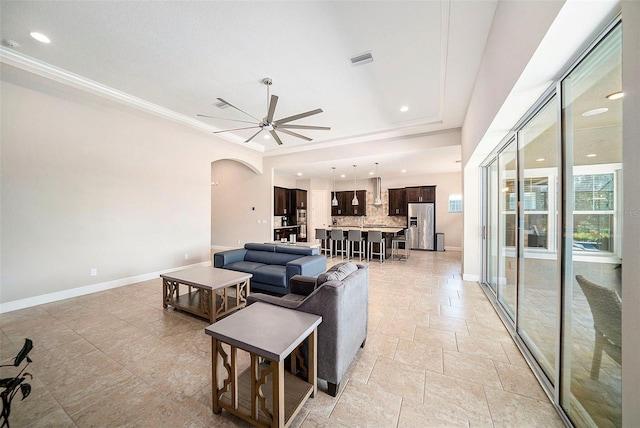 8016 Rock Spring Ct, Land O Lakes, FL 34638 - living room with arched walkways, a ceiling fan, crown molding, stone tile floors, and recessed lighting