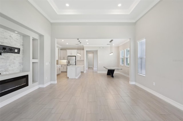 4325 Barletta Ct, Wesley Chapel, FL 33543 - unfurnished living room featuring ornamental molding, a large fireplace, a raised ceiling, light wood-style flooring, and recessed lighting
