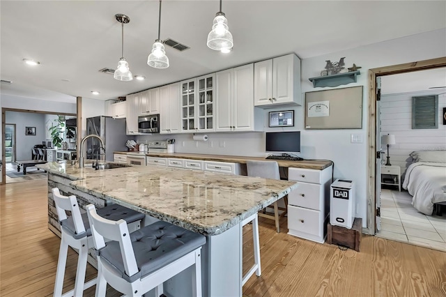 550 George St S, Tarpon Springs, FL 34688 - kitchen featuring appliances with stainless steel finishes, a breakfast bar area, a sink, white cabinets, and light wood-style flooring