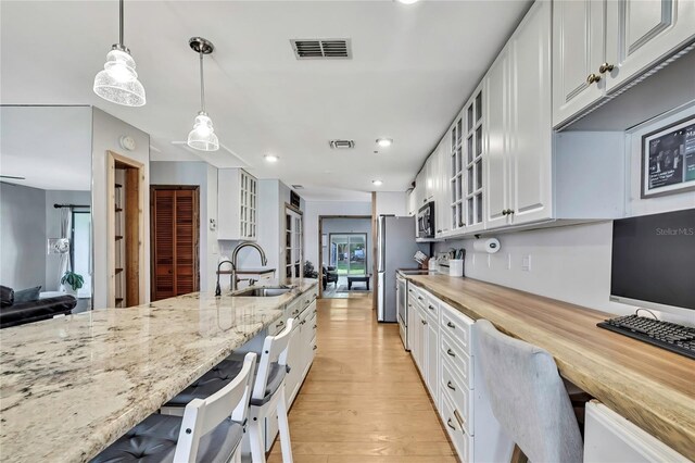 550 George St S, Tarpon Springs, FL 34688 - kitchen featuring white cabinets, stainless steel appliances, light wood-type flooring, light stone countertops, and recessed lighting